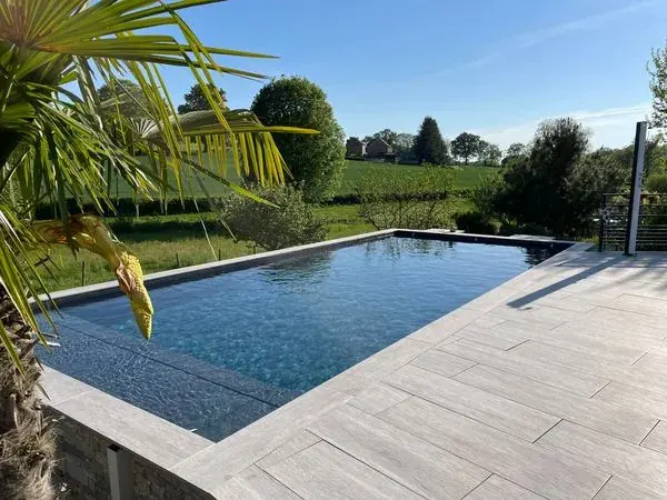Bassin effet miroir – Revêtement sombre et plage en lames de bois.