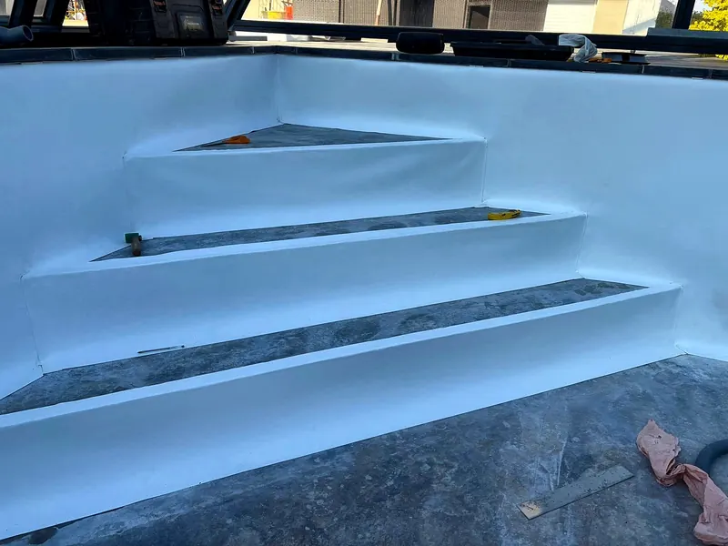 PVC armé – Pose du PVC armé blanc sur un escalier d’angle, en cours de chantier.