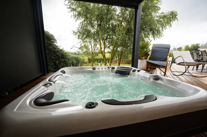 Spa sous pergola – Spa sur terrasse bois, sous pergola, avec vue sur la campagne.